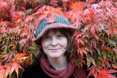 Woman smiling in red foliage with knitted hat