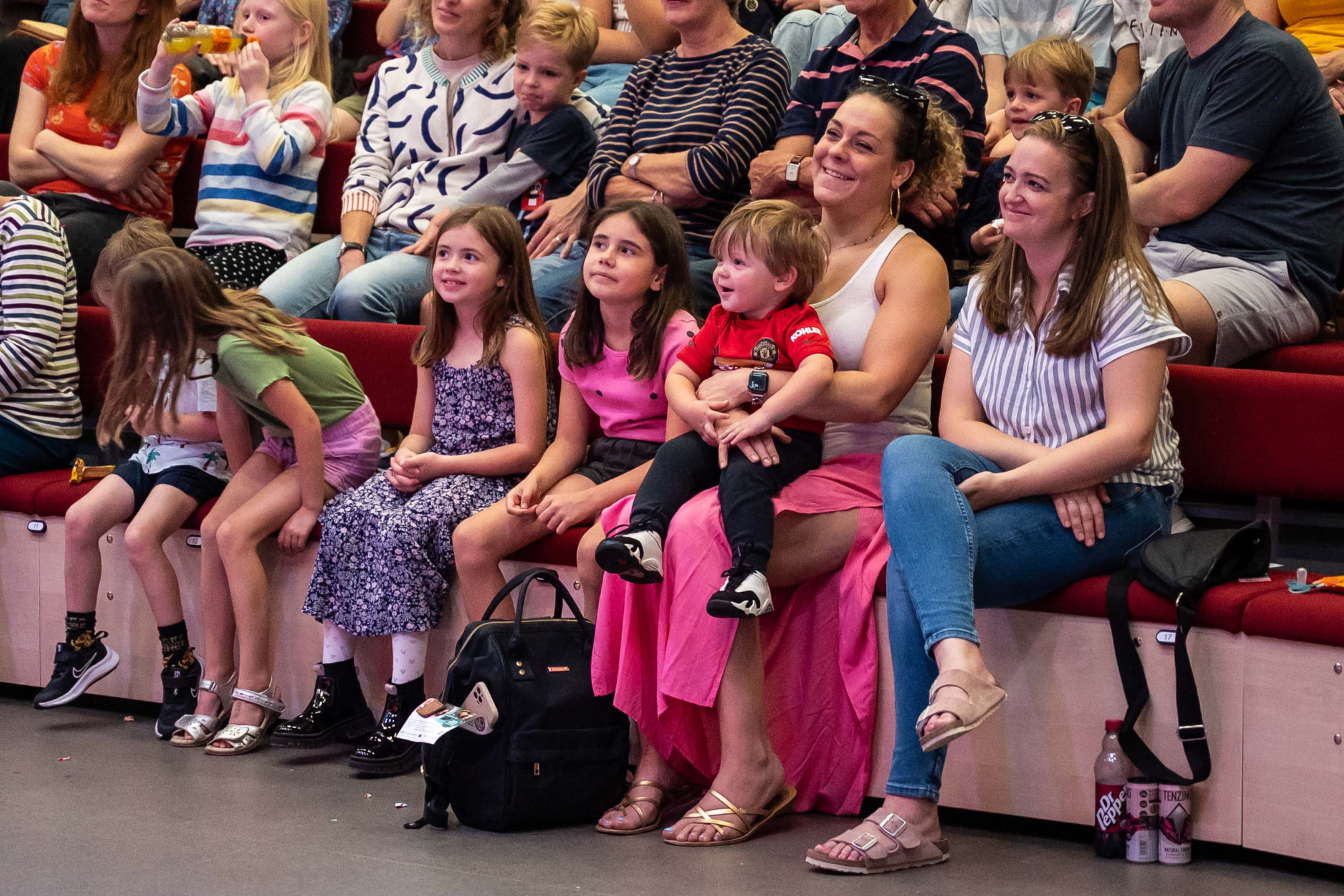 Audience members sat in the front row smiling. There is a selection of adults and children.