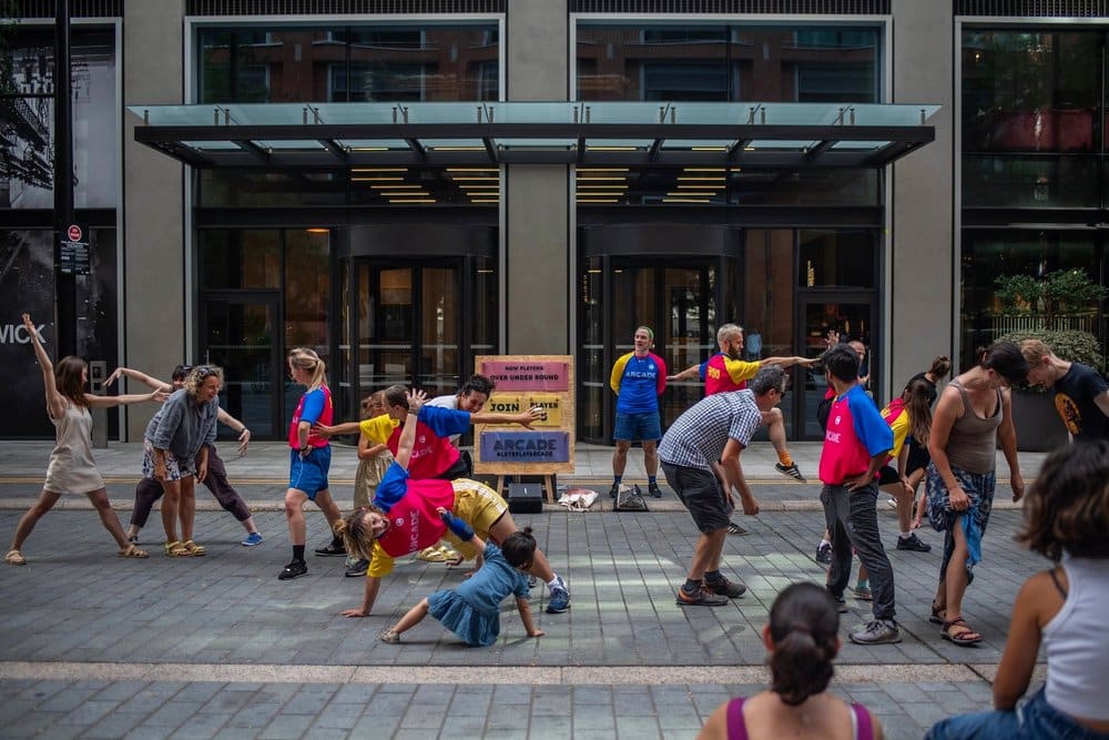 Large group of people outside in the street making different shapes with their bodies