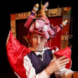 Performer Jon Hicks wearing a colourful costume and hat